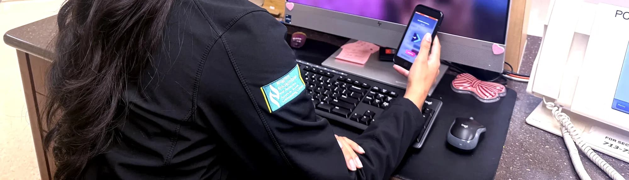 A nurse at a workstation using CareShift on her phone while she charts